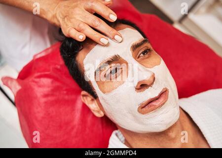 Un spécialiste de beauté applique un soin du visage sur le front d'un adulte Banque D'Images