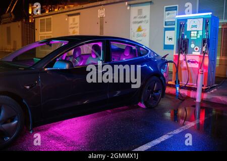 La voiture électrique noire se recharge dans une station de charge EV contemporaine Banque D'Images