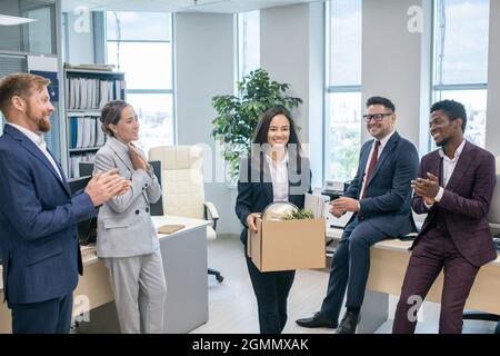Un groupe de gens d'affaires qui réussissent à porter des vêtements de formal saluent un nouvel employé en se claquant les mains Banque D'Images