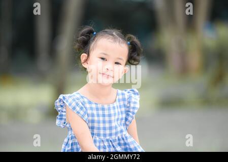 Enfant asiatique fille heureux dans le parc jardin arbre arrière-plan, beau enfant ayant l'amusement jouer à l'extérieur avec heureux sourire enfants jouant à l'extérieur peu Banque D'Images