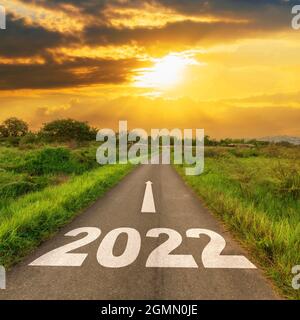 Route asphaltée vide et concept du nouvel an 2022. Conduite sur une route vide jusqu'aux objectifs 2022 avec coucher de soleil. Banque D'Images