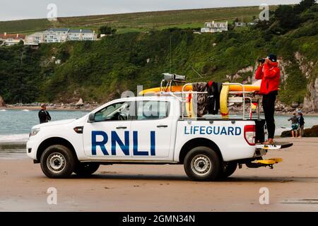 Un sauveteur surveille les nageurs à travers des jumelles d'un véhicule de patrouille RNLI stationné sur Bantham Beach, Devon. Banque D'Images