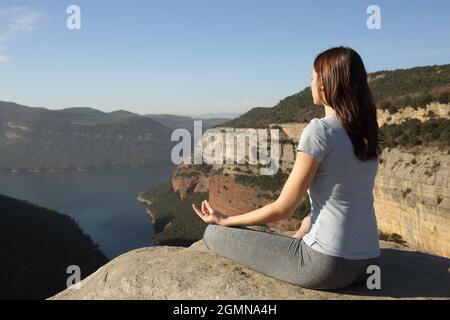 Femme faisant le yoga lotus poser sur le sommet d'une falaise Banque D'Images