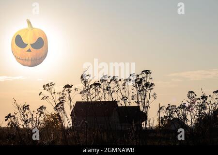 Concept Halloween. Mystérieuse maison abandonnée au coucher du soleil dans la lumière sombre. Lanterne Jack Pumpkin transparente au lieu de la lune. Les mauvaises herbes sont dans le foregrou Banque D'Images