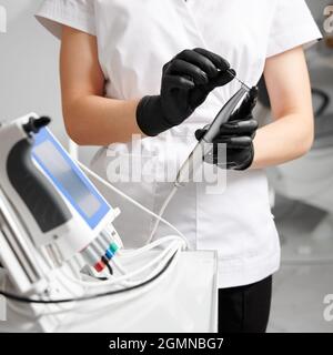 Gros plan des mains des femmes médecins dans des gants stériles tenant l'endodontie pour le traitement du canal racinaire. Femme stomatologiste préparant un dispositif endodontique pour l'intervention dentaire. Concept de la dentisterie. Banque D'Images