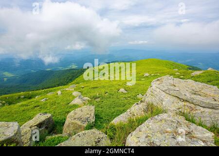 vue depuis la montagne runa. pierres immenses sur les pistes herbeuses. paysage d'été des montagnes carpathes. bieszczady et crête vihorlat au loin ben Banque D'Images