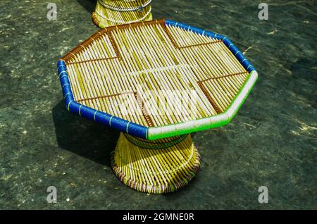 Mise au point sélective sur UNE TABLE RONDE EN BAMBOU sous le soleil du matin. Élégante table en bambou avec corde bleue et verte. Artisanat indien fait à la main. Banque D'Images