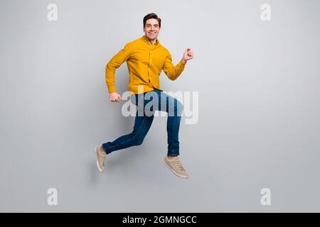 Vue sur toute la longueur du corps de l'homme gai attrayant saut aller bonne humeur isolée sur fond gris couleur Banque D'Images