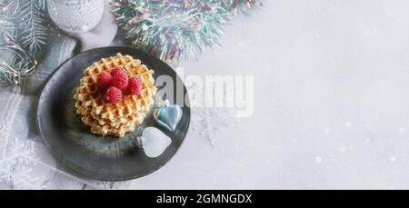 Gaufres rondes avec framboises sur la table de Noël. Pâtisseries festives sur le fond d'un arbre de Noël. Espace de copie, bannière. Banque D'Images