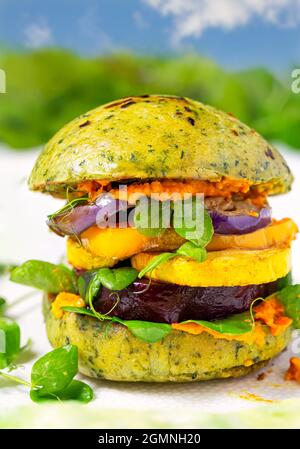 Gros plan d'un hamburger à base de légumes rôtis sur un pain infusé aux épinards et sauce à la carotte Banque D'Images