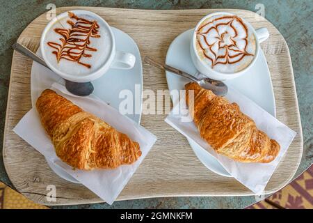 Vue de dessus sur le petit déjeuner avec croissant et cappuccino dans un café italien en Suisse. Voyage vacances en Suisse, Tessin Canton. Banque D'Images