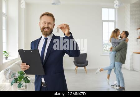 Agent immobilier ou agent immobilier montre les clés de la maison qu'il a vendu à un jeune couple Banque D'Images