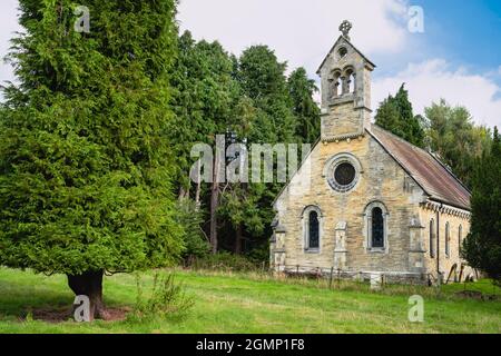 Ancienne église traditionnelle, aujourd'hui déserte, flanquée d'arbres dans un paysage rural flanqué de grands sapins et de prairies près du village de Kilnwick Percy, Royaume-Uni Banque D'Images