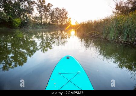 Panneau de paddle-board gonflable SUP sur la rivière d'été au lever du soleil Banque D'Images