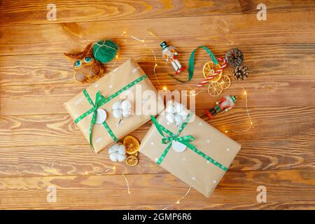 Cadeaux de Noël sur table en bois. Boîtes en papier d'emballage avec motifs attachés avec des rubans avec flocons de neige. Jouets soldats, café chouette fait main, cônes et coton sur fond. L'atmosphère du nouvel an. Banque D'Images