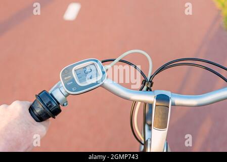 Point de vue de la première personne sur le panneau de commande sur le guidon du vélo électrique en conduisant sur la voie du vélo Banque D'Images