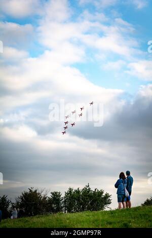Sidmouth, septembre 2021: Un jeune couple caucasien regardant les flèches rouges (RAF) se produire avec leurs avions à réaction BAE Hawk au salon de l'air de Sidmouth Banque D'Images