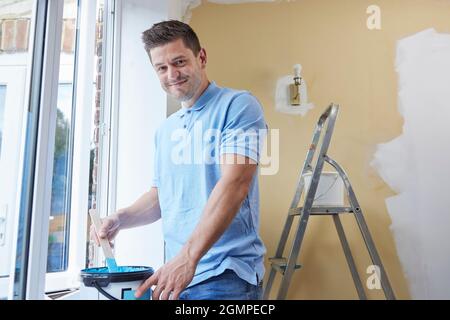 Portrait de l'homme remuant la peinture avant de décorer la pièce à la maison Banque D'Images