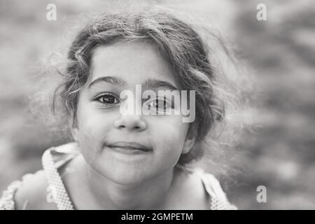 Noir et blanc Portrait d'une petite fille mignonne souriante au parc d'été. Enfant heureux regardant la caméra Banque D'Images