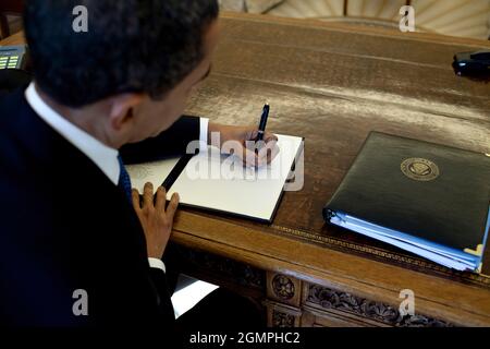 Le Président Barack Obama écrit à son bureau dans le Bureau ovale 3/3/09. Photo officielle de la Maison Blanche par Pete Souza Banque D'Images
