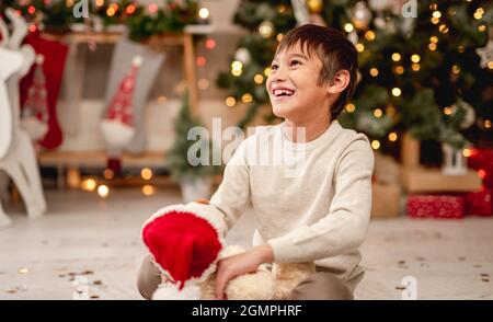 Petit garçon avec peluche dans un chapeau de père noël Banque D'Images