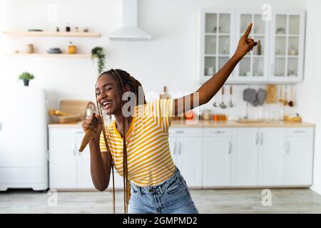 Jeune femme noire s'amusant en cuisinant dans la cuisine Banque D'Images