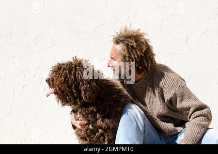 un homme d'âge moyen hople son chien, ils sont assis et regardent au même point Banque D'Images