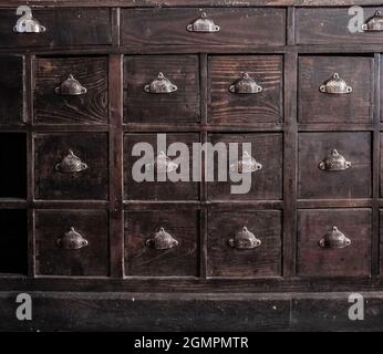 Mobilier en bois brun foncé pour tiroirs. Poignées en métal en forme de coque Banque D'Images