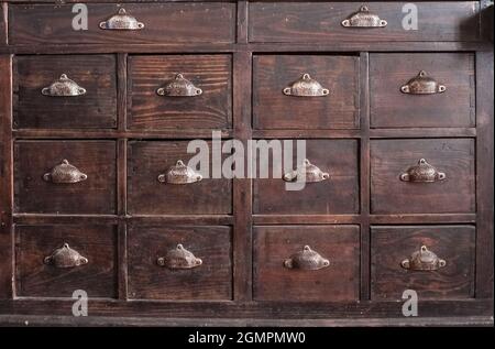 Mobilier en bois brun foncé pour tiroirs. Poignées en métal en forme de coque Banque D'Images