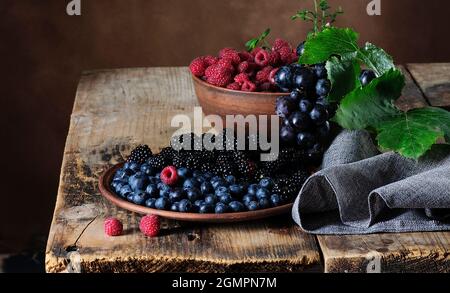 Framboises mûres, mûres, bleuets, raisins sur une table en bois vintage Banque D'Images