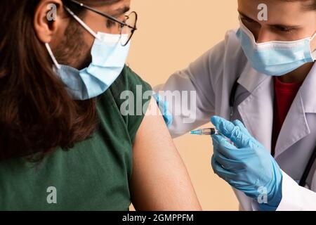 Femme médecin effectuant une injection intramuscualr pour un homme arabe à la clinique Banque D'Images