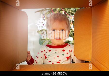 Un garçon souriant et heureux regarde à l'intérieur de la boîte à présent Banque D'Images