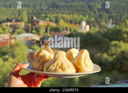 Assiette de boulettes de soupe traditionnelle géorgienne appelées Khinkali dans la main de la femme Banque D'Images