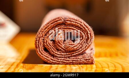 Torchon à vaisselle trois plis en microfibre brun enroulé sur une surface en bois Banque D'Images