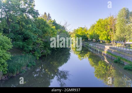 Opole, Pologne - 4 juin 2021 : vue d'été sur le canal de Mlynowka entre les arbres dans le centre-ville d'Opole. Banque D'Images