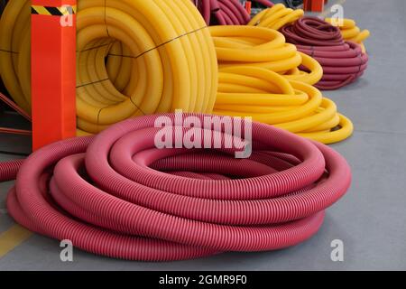 Tuyau flexible de drainage terrestre à bobine jaune et rouge, tas fendu en magasin. Banque D'Images