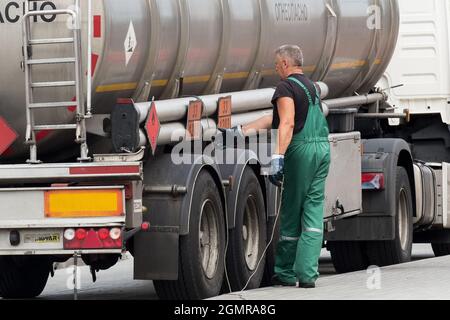 Bélarus, région de Gomel - 21 août 2020 : un conducteur de camion en combinaison saisit le cordon ou le fil de mise à la terre pour mettre la machine à la terre. Transport et délaque Banque D'Images