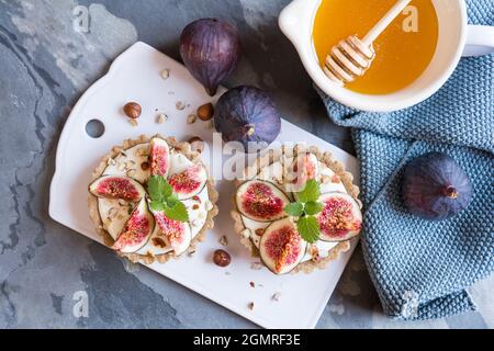 Tartelettes à la farine d'épeautre remplies de yaourt grec, de figues, de noisettes et de miel Banque D'Images