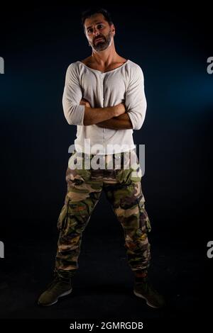 Jeune homme cool habillé de chemise blanche posant dans l'obscurité studio Banque D'Images