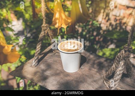 Café dans une tasse en papier écologique dans le jardin d'automne Banque D'Images