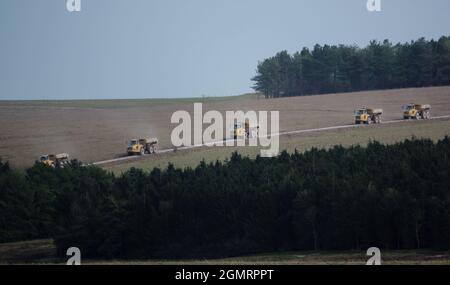 Cinq engins de terrassement articulés Volvo A40E jaunes traversant la plaine de Salisbury, Wiltshire, Royaume-Uni Banque D'Images