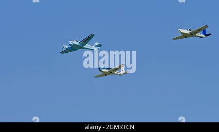 Trois avions légers volant en formation contre un ciel bleu clair lors d'un spectacle d'aviation. Banque D'Images