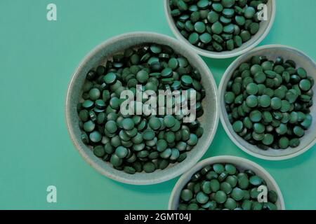 Comprimés d'algues de spiruline. Spiruline comprimés dans les tasses sur un fond vert. Oméga-3 végétarien. Source d'acides aminés et oméga-3. Oméga-3 Banque D'Images