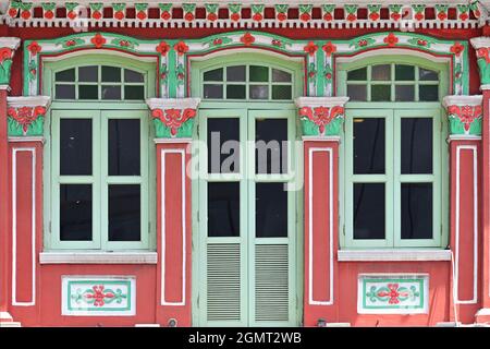 Façade du magasin Peranakan du détroit de Red Singapore avec fenêtres voûtées, volets en bois clair vert perlé et colonnes ornées de finitions Banque D'Images