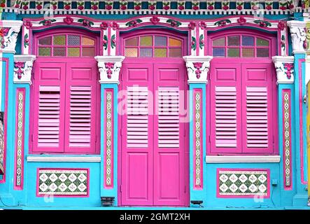 Façade du magasin Peranakan chinois Blue Singapore Straits avec fenêtres voûtées, volets à persiennes roses et colonnes ornées de finitions florales Banque D'Images