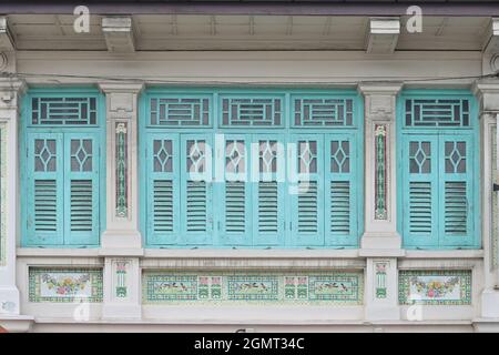 White Singapore Straits Chinese Peranakan Shop House avec volets en bois bleu clair, colonnes ornées, mosaïques avec motifs fleurs et oiseaux Banque D'Images