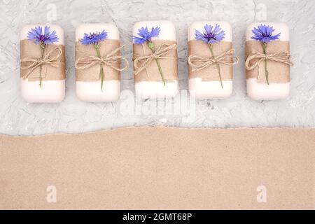 Savon naturel fait main décoré de papier artisanal, de fléau et de fleurs bleues. Concept de cosmétiques biologiques. Vue de dessus modèle d'espace de copie de la pose à plat pour d Banque D'Images