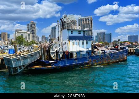 Vieux chalutier de pêche commerciale rouillé, amarré dans le port de San Diego, sur fond de bâtiments élevés dans le centre-ville de San Diego, CA Banque D'Images