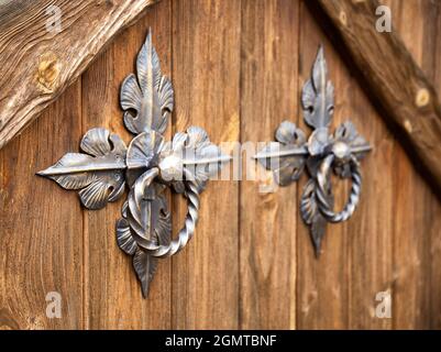 Poignées de porte sur une porte en bois sous forme d'anneaux en bronze forgé, gros plan Banque D'Images