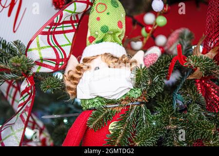Petit ornement de Noël bourré d'elf avec un masque sur son visage sur un arbre de Noël 2020. Banque D'Images